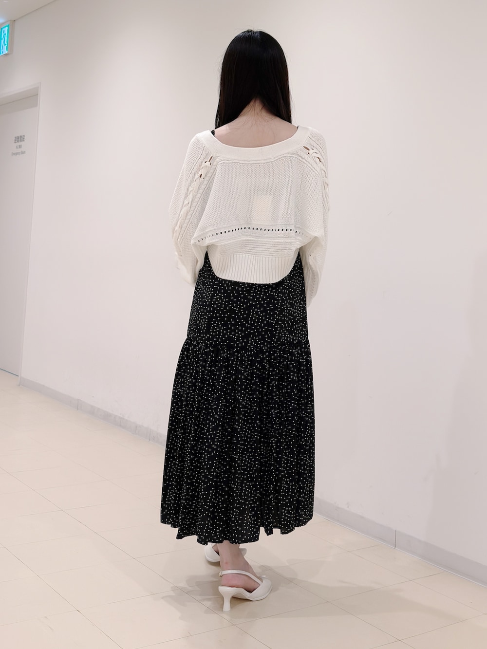 ブラック系のワンピース、ホワイト系のカーディガン/ボレロ、ホワイト系のパンプスを着用したレディースの秋コーディネートの4枚目の写真