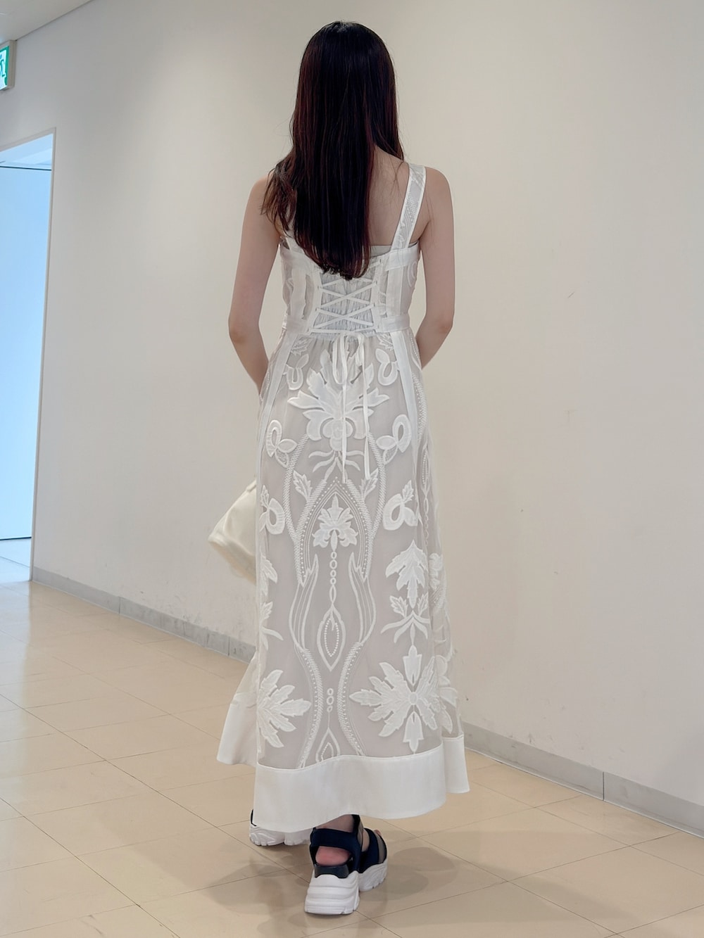 ホワイト系のワンピース、ホワイト系のハンドバッグ、ブラック系のサンダルを着用したレディースの夏コーディネートの5枚目の写真