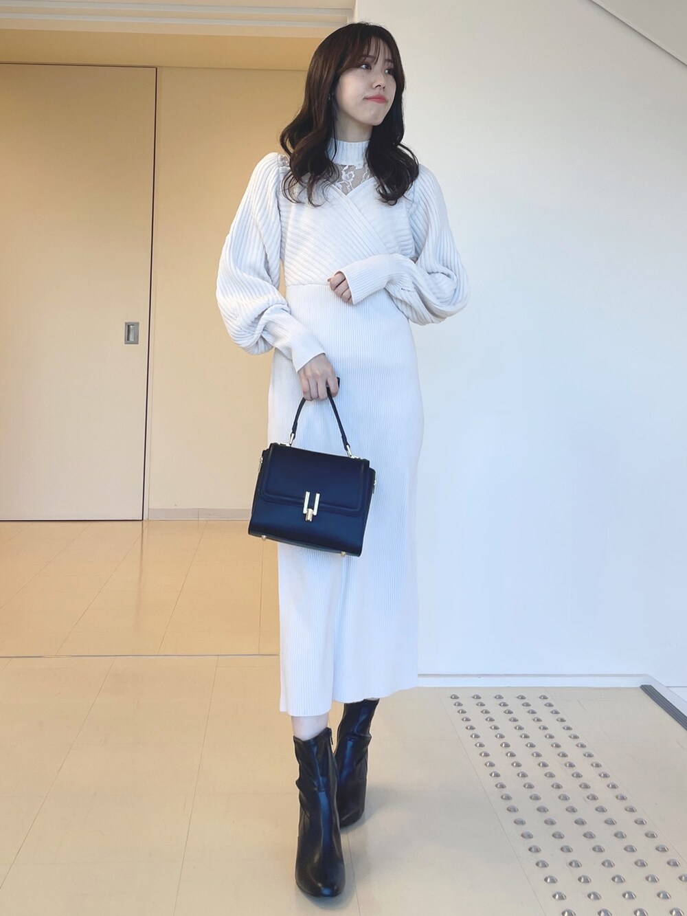 ホワイト系のワンピース、ブラック系のブーツ、ブラック系のショルダーバッグを着用したレディースの秋コーディネートの3枚目の写真