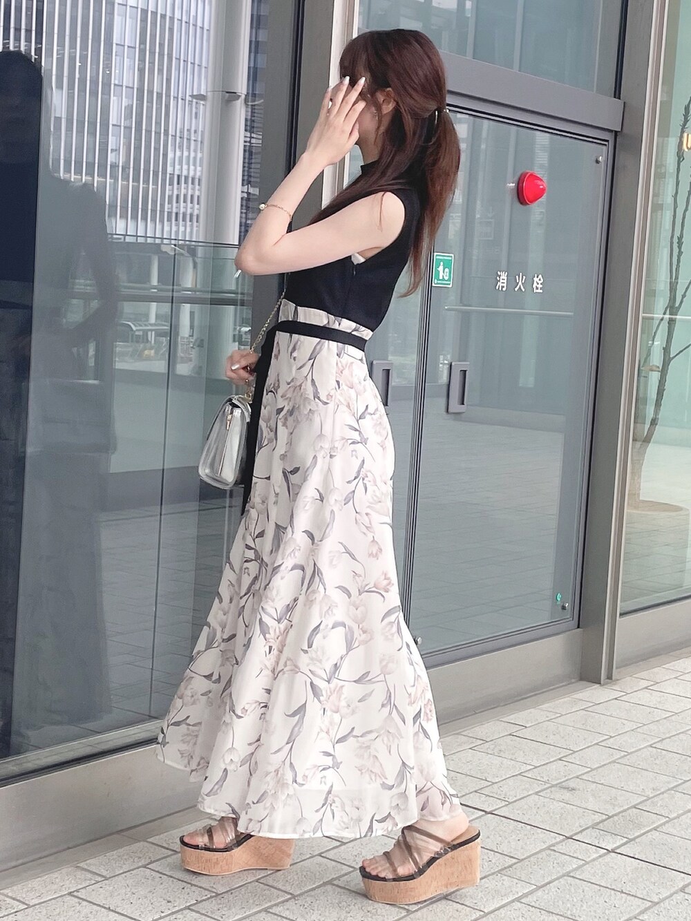 シルバー系のハンドバッグ、ブラック系のワンピース、ブラック系のサンダルを着用したレディースの春コーディネートの5枚目の写真