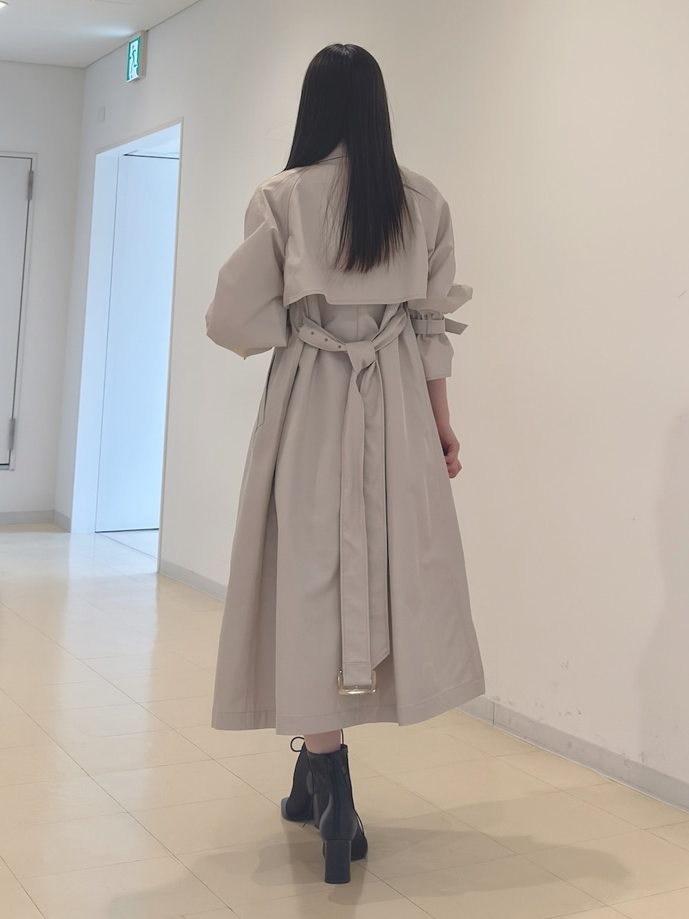 ベージュ系のトレンチコート、ホワイト系のニット/セーター、ブラック系のスカートを着用したレディースの春コーディネートの5枚目の写真