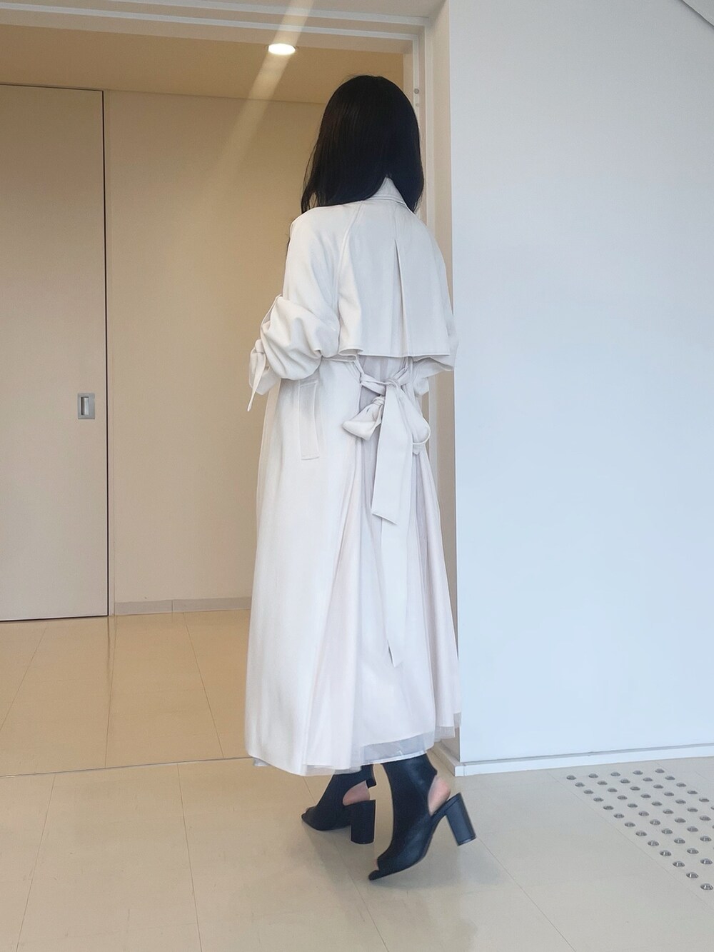 ベージュ系のワンピース、ブラック系のブーツ、ホワイト系のトレンチコートを着用したレディースの春コーディネートの4枚目の写真