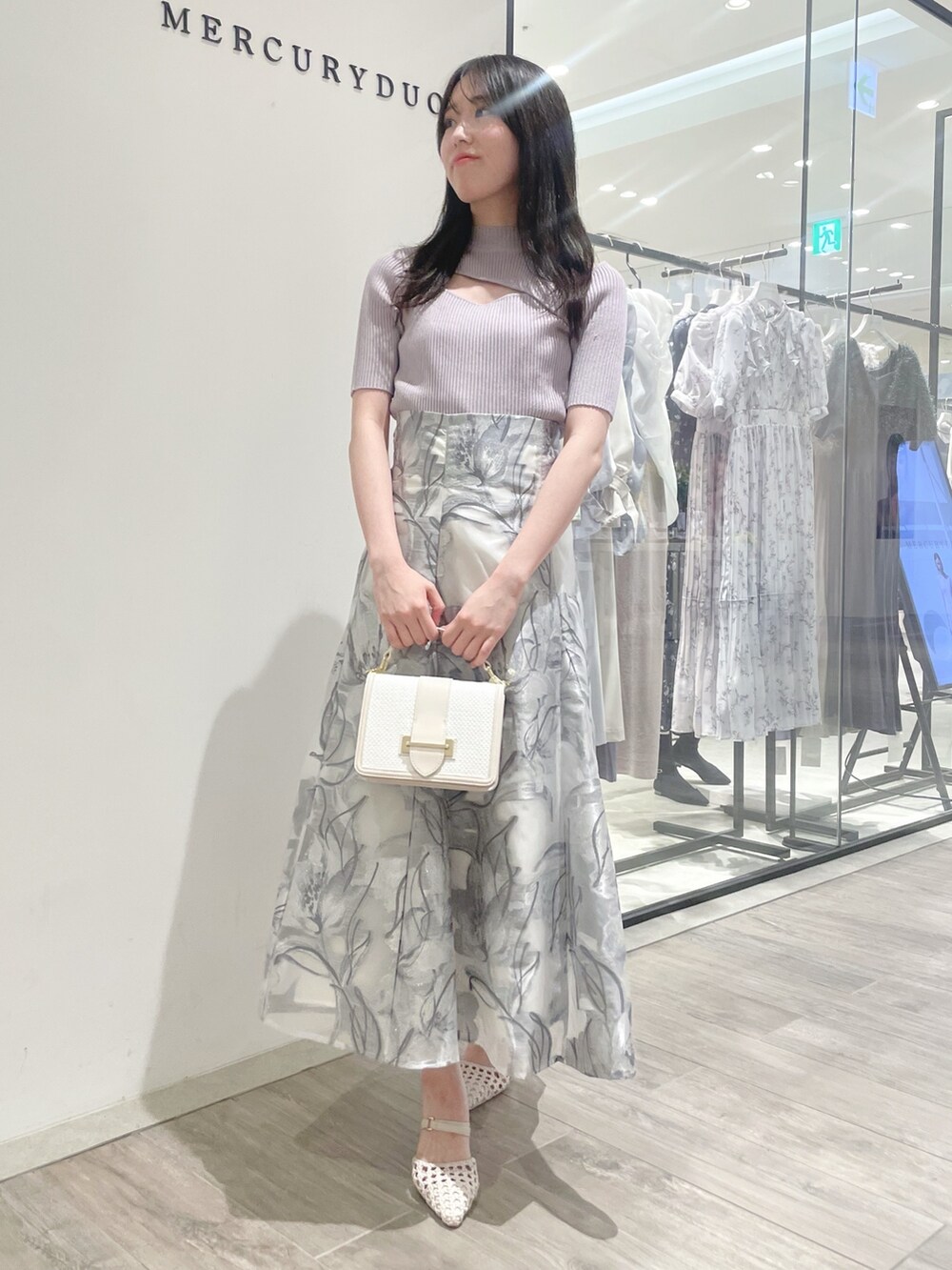 ホワイト系のパンプス、ピンク系のニット/セーター、グレー系のスカートを着用したレディースの春コーディネートの2枚目の写真