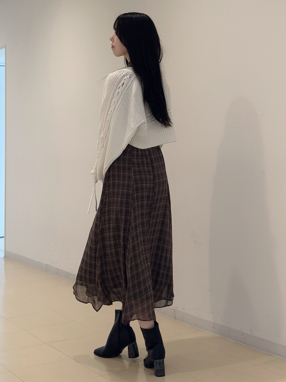 ホワイト系のカーディガン/ボレロ、ブラウン系のワンピース、ブラック系のブーツを着用したレディースの夏コーディネートの2枚目の写真