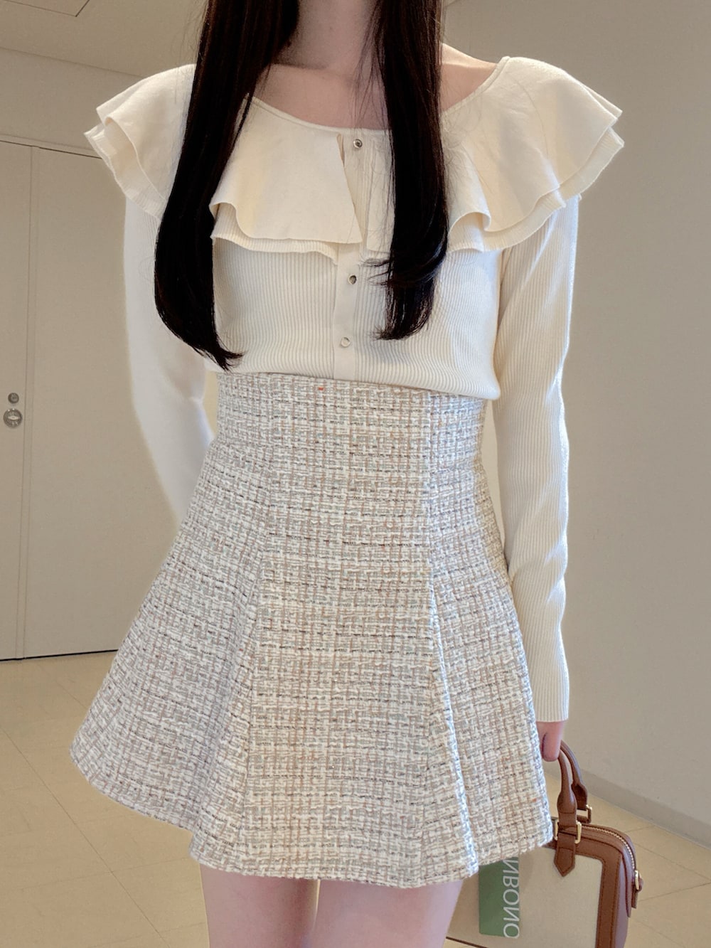 ホワイト系のニット/セーター、ベージュ系のスカート、ブラウン系のハンドバッグを着用したレディースの冬コーディネートの5枚目の写真