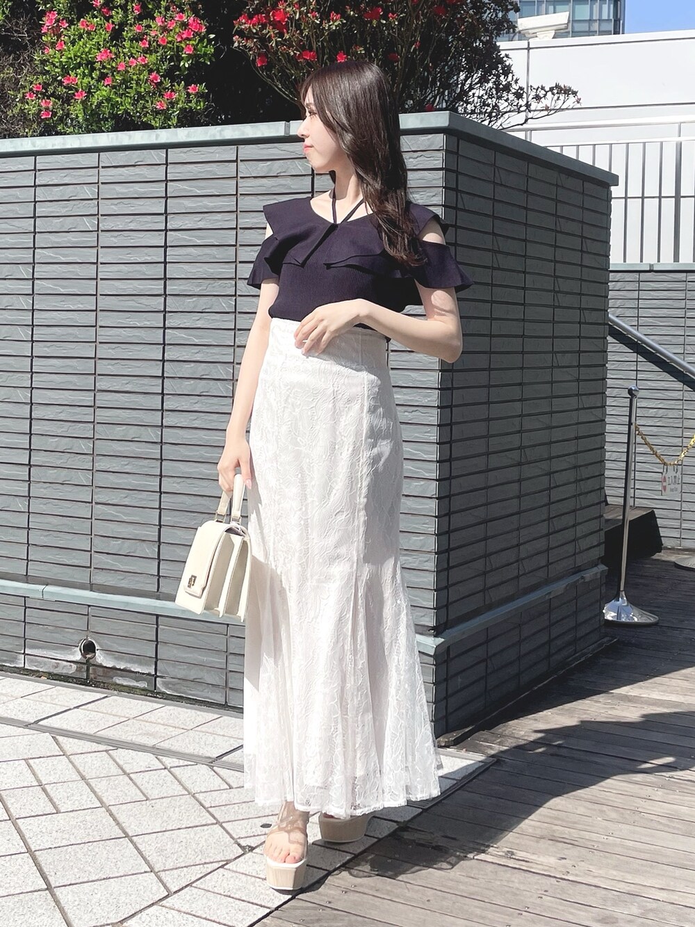 ブルー系のニット/セーター、ホワイト系のスカート、ホワイト系のハンドバッグを着用したレディースの春コーディネートの3枚目の写真