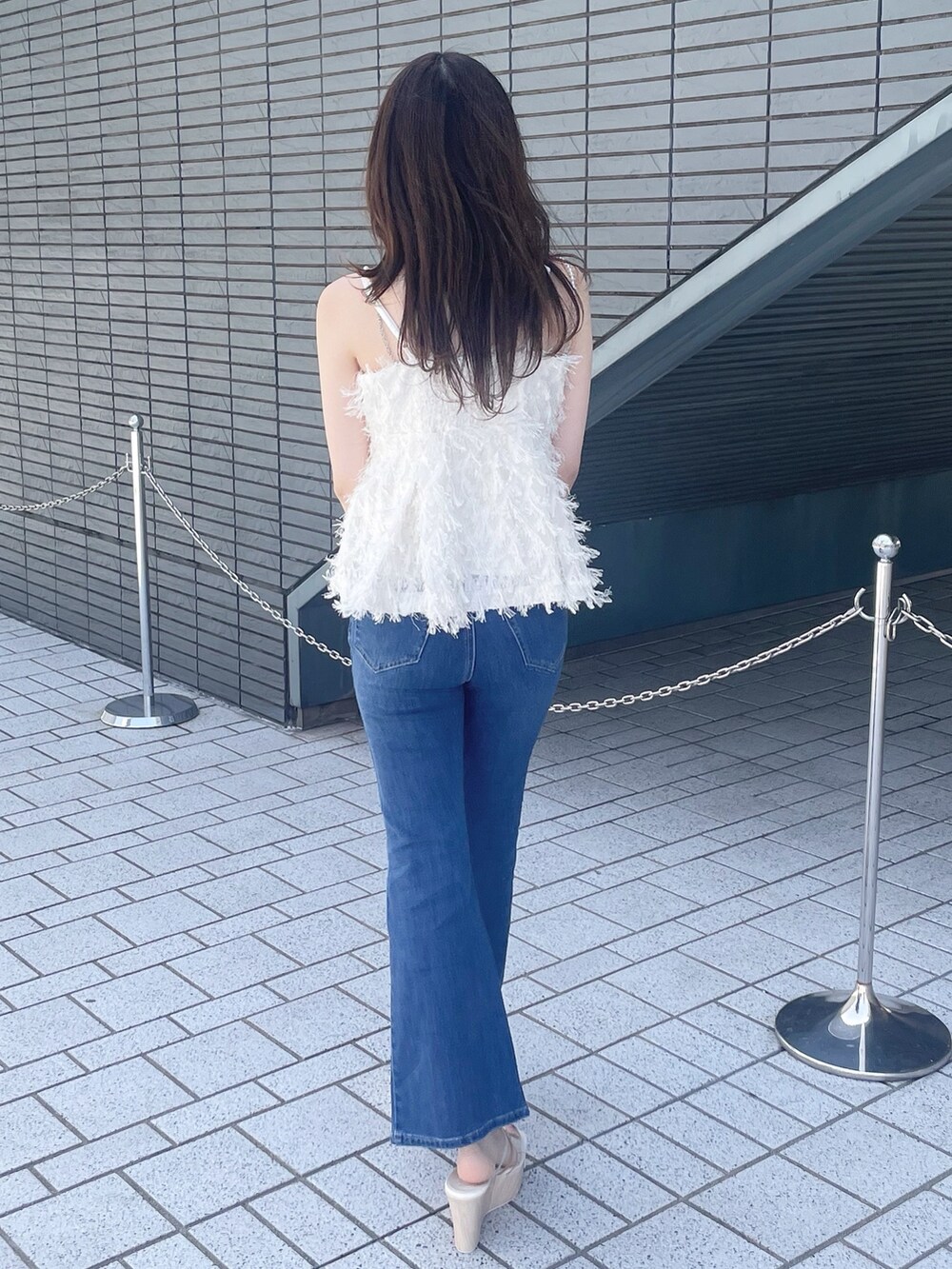 ホワイト系のキャミソール、ブルー系のデニムパンツ、その他のサンダルを着用したレディースの春コーディネートの6枚目の写真