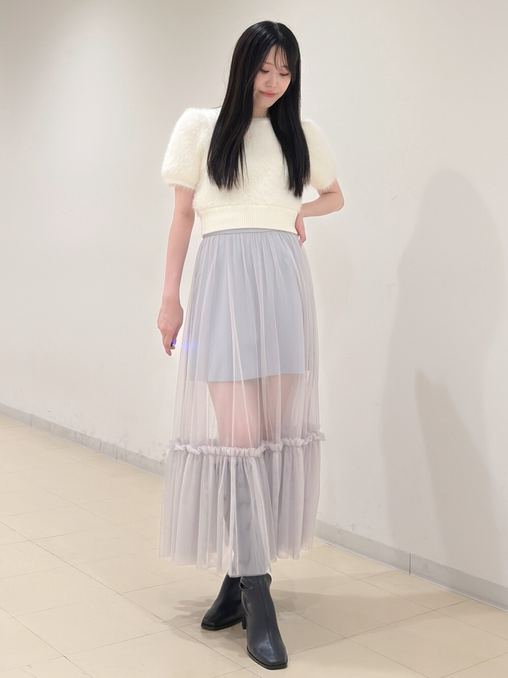 ホワイト系のニット/セーター、ブルー系のスカート、ブラック系のブーツを着用したレディースの夏コーディネートの3枚目の写真