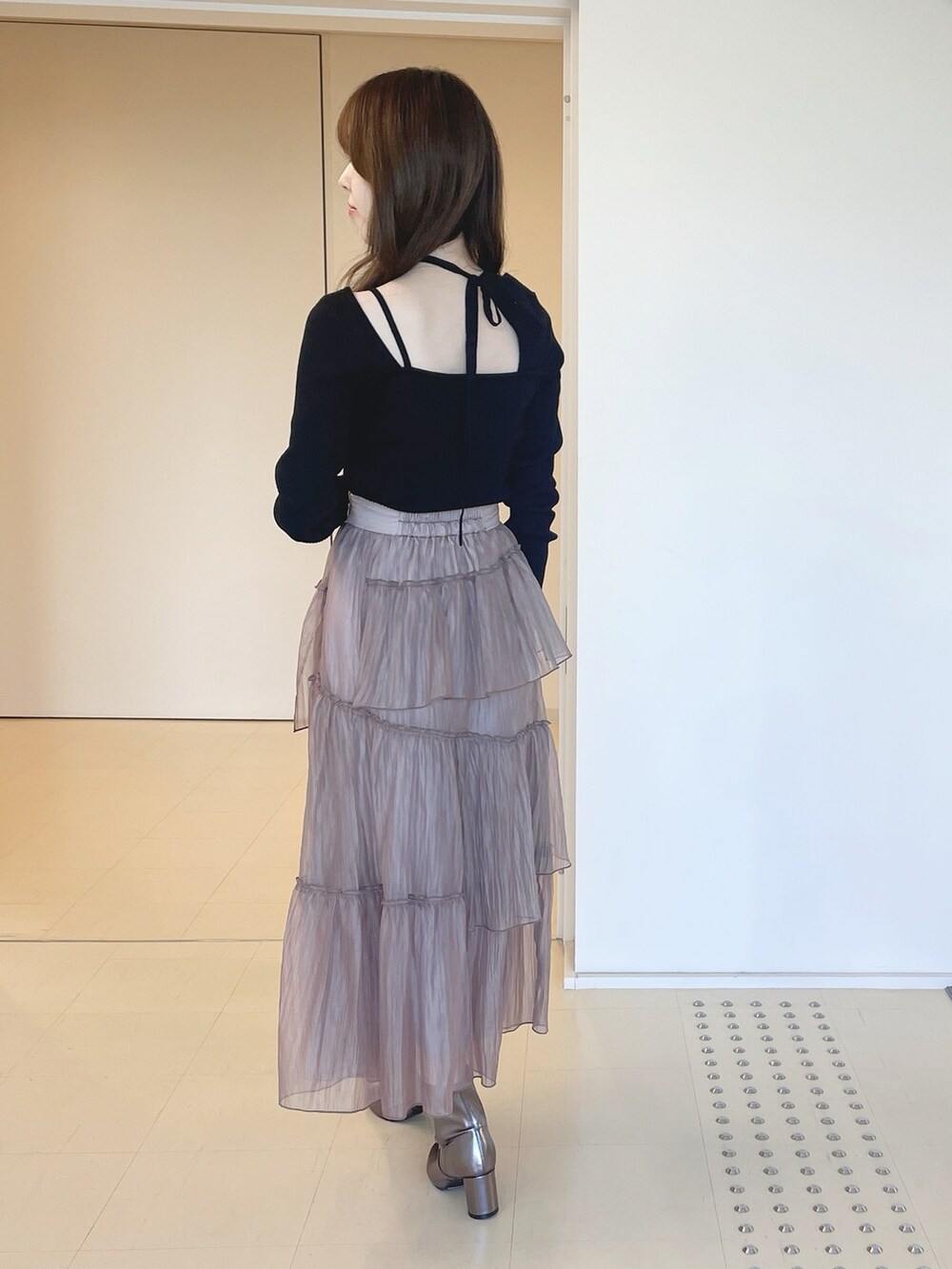 ゴールド系のブーツ、ブラウン系のスカート、ブラック系のニット/セーターを着用したレディースの冬コーディネートの5枚目の写真