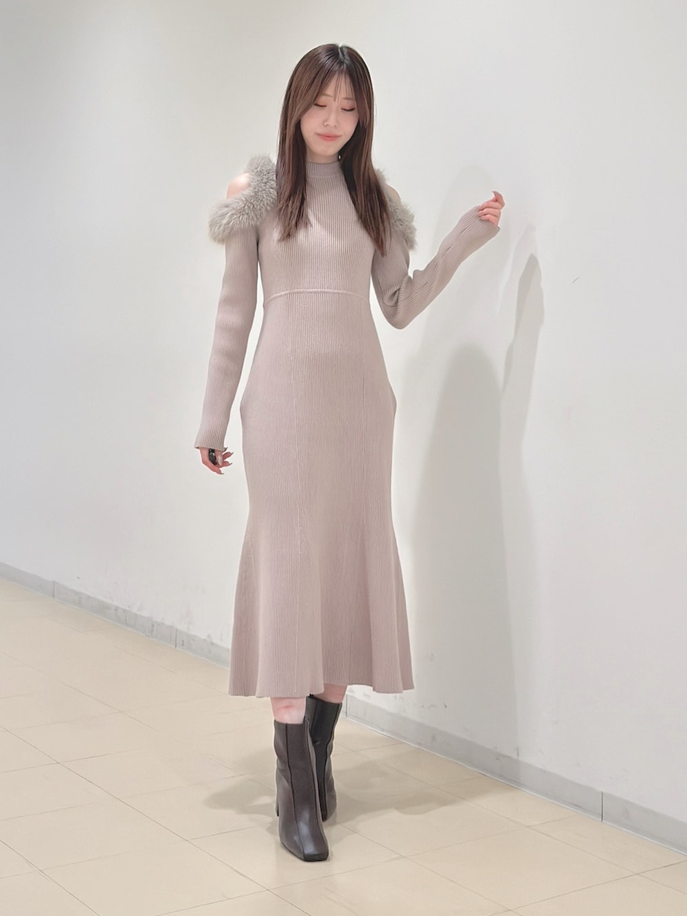 ベージュ系のワンピース、ホワイト系のハンドバッグ、ブラウン系のブーツを着用したレディースの冬コーディネートの5枚目の写真