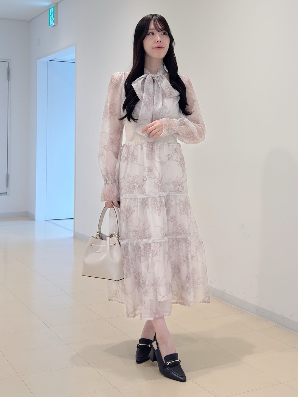 ベージュ系のワンピース、ホワイト系のショルダーバッグ、ブラウン系のパンプスを着用したレディースの冬コーディネートの5枚目の写真