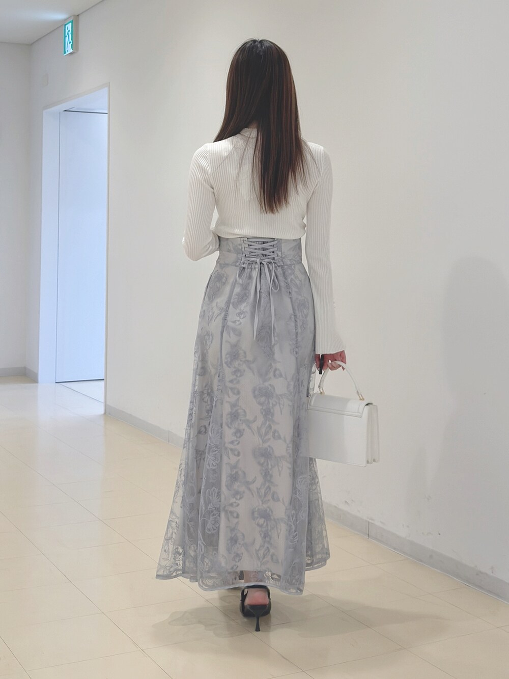 ホワイト系のニット/セーター、ブルー系のスカート、ホワイト系のハンドバッグを着用したレディースの冬コーディネートの5枚目の写真