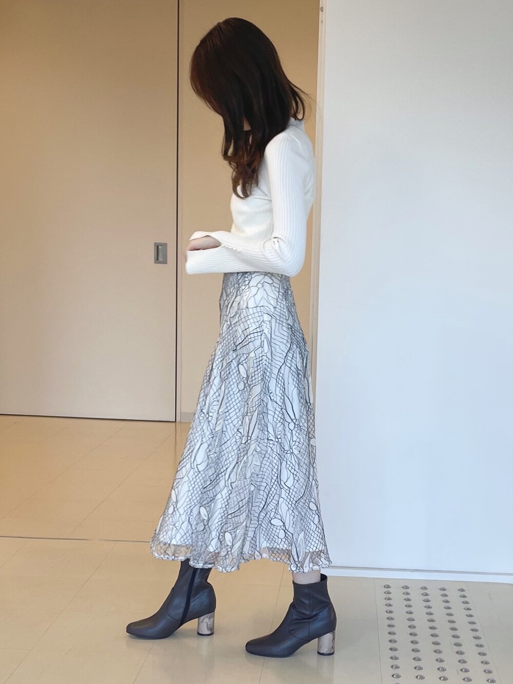 ベージュ系のトレンチコート、ホワイト系のニット/セーター、ホワイト系のスカートを着用したレディースの冬コーディネートの4枚目の写真