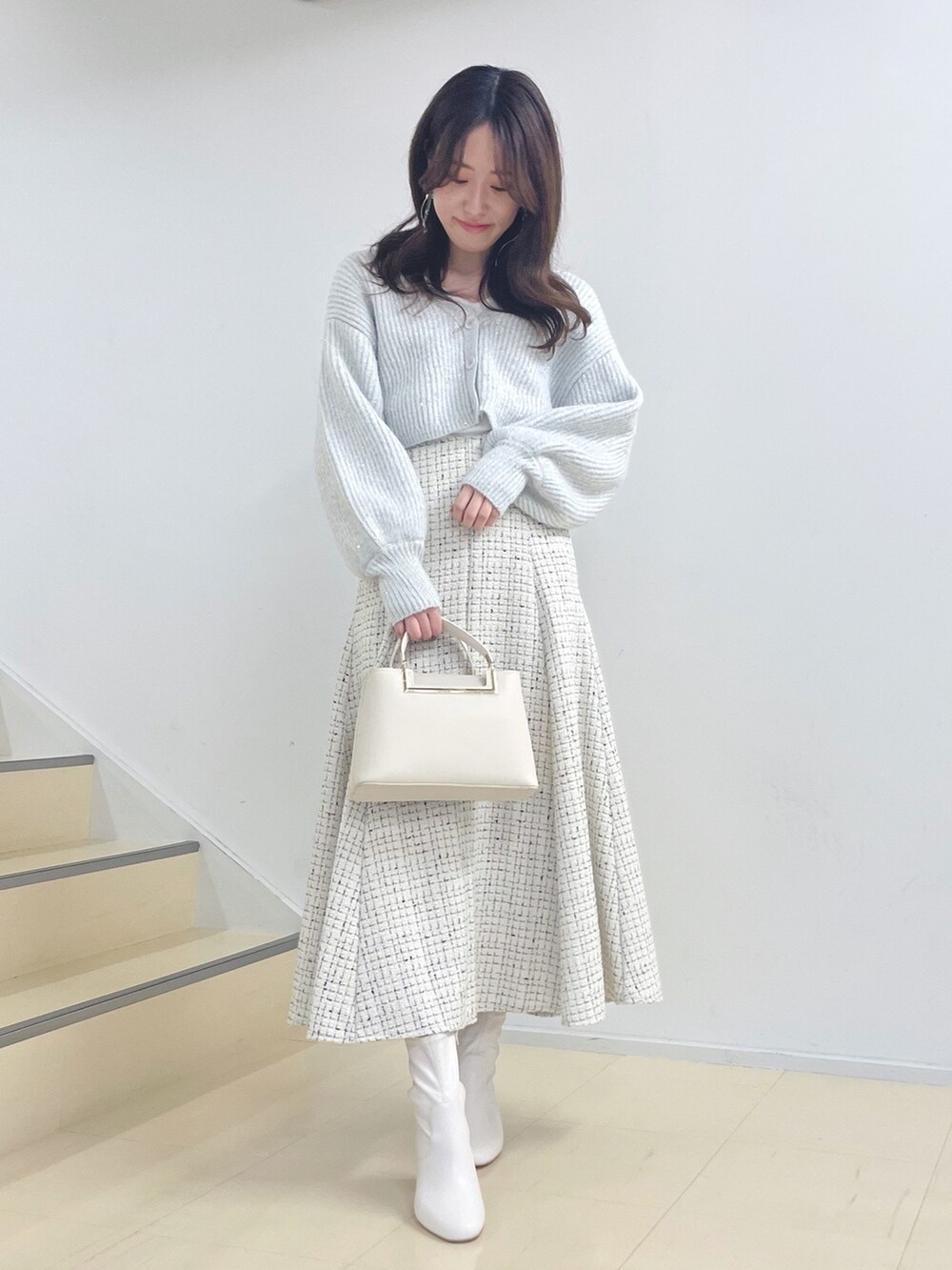 ホワイト系のニット/セーター、ホワイト系のスカート、ホワイト系のハンドバッグを着用したレディースの秋コーディネートの2枚目の写真