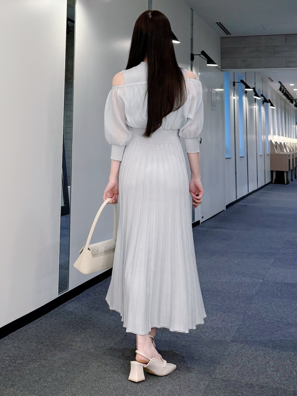 グレー系のワンピース、ホワイト系のハンドバッグ、ホワイト系のパンプスを着用したレディースの春コーディネートの4枚目の写真