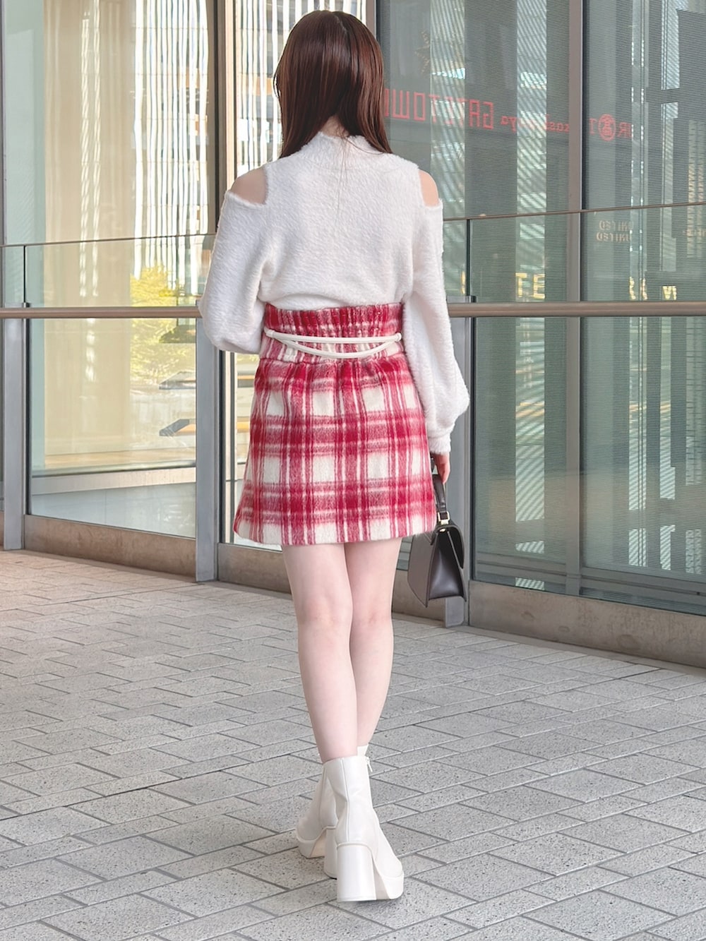 ブラウン系のチェスターコート、ホワイト系のニット/セーター、レッド系のその他パンツを着用したレディースの冬コーディネートの6枚目の写真