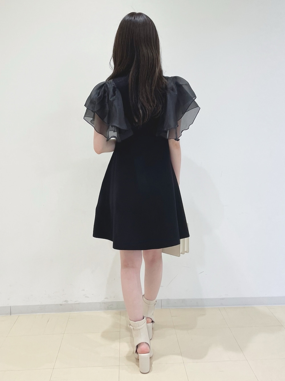 ブラック系のワンピース、ホワイト系のハンドバッグ、ホワイト系のブーツを着用したレディースの春コーディネートの6枚目の写真