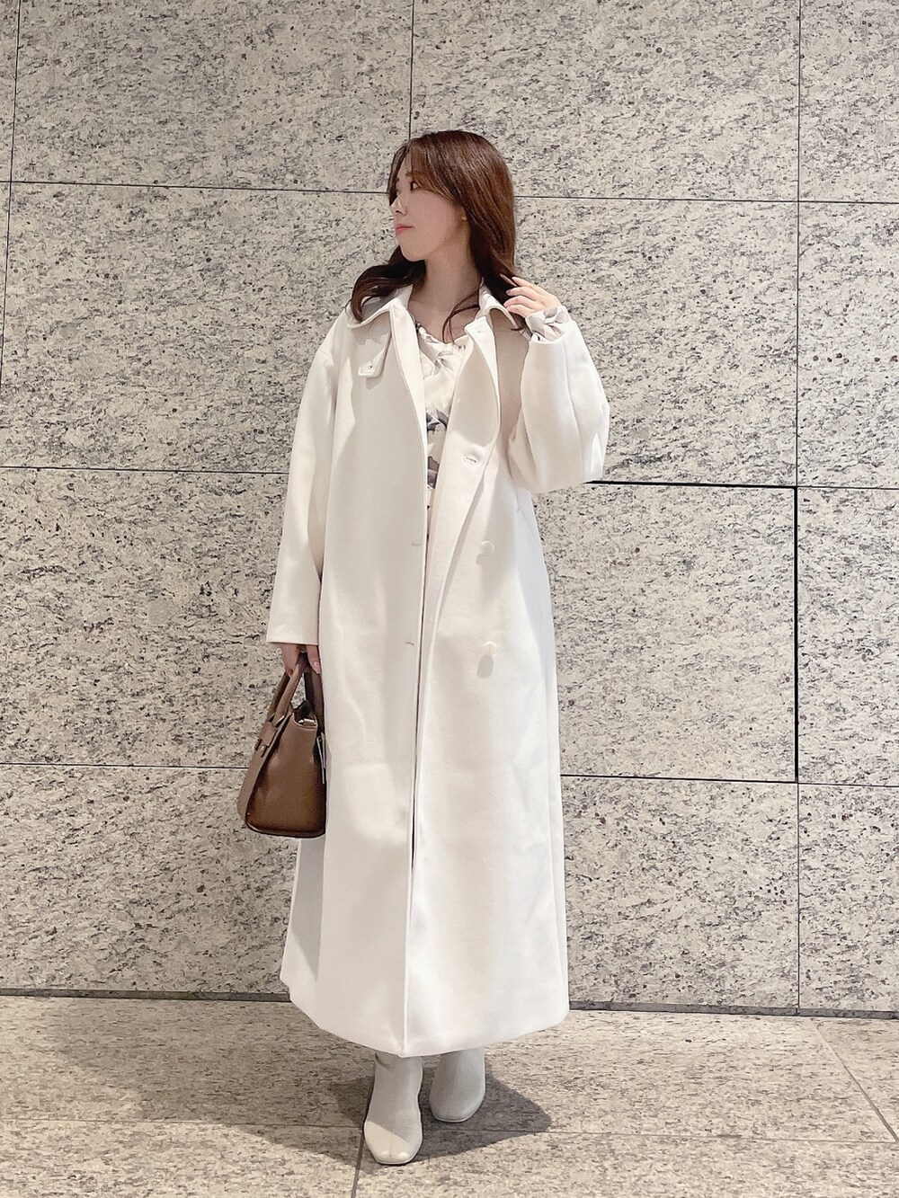 ホワイト系のステンカラーコート、ホワイト系のワンピースを着用したレディースの冬コーディネートの3枚目の写真