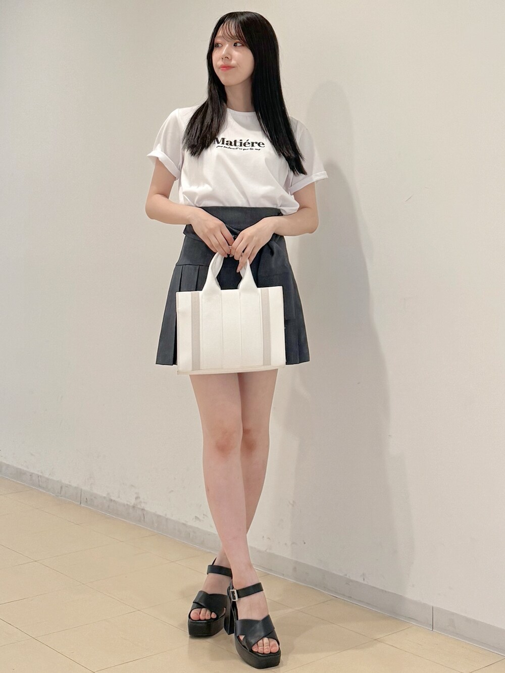 ホワイト系のTシャツ/カットソー、グレー系のスカート、ホワイト系のトートバッグを着用したレディースの春コーディネートの2枚目の写真