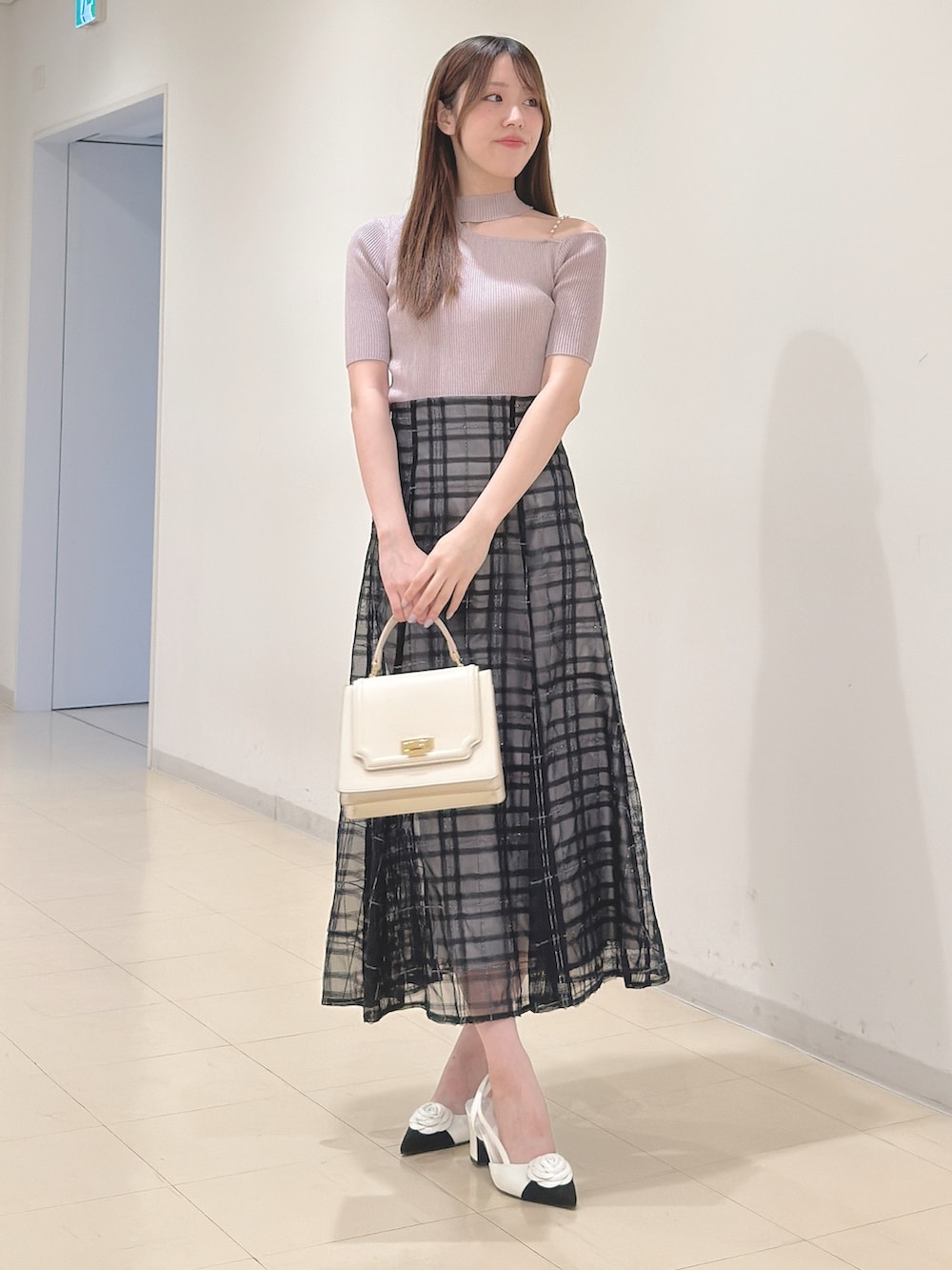 ベージュ系のニット/セーター、ブルー系のスカート、ホワイト系のハンドバッグを着用したレディースの春コーディネートの2枚目の写真