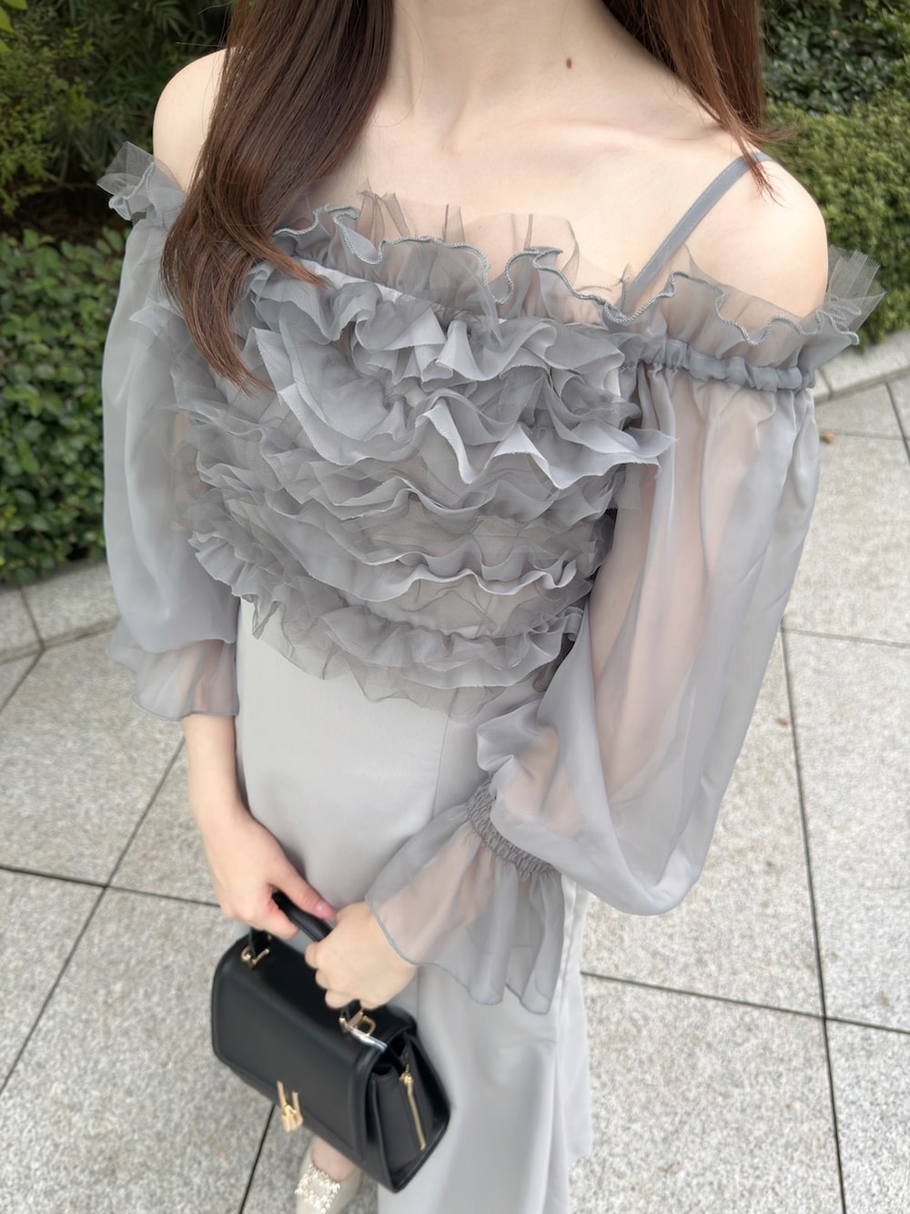 グレー系のワンピース、ブラック系のハンドバッグ、ホワイト系のパンプスを着用したレディースの秋コーディネートの7枚目の写真