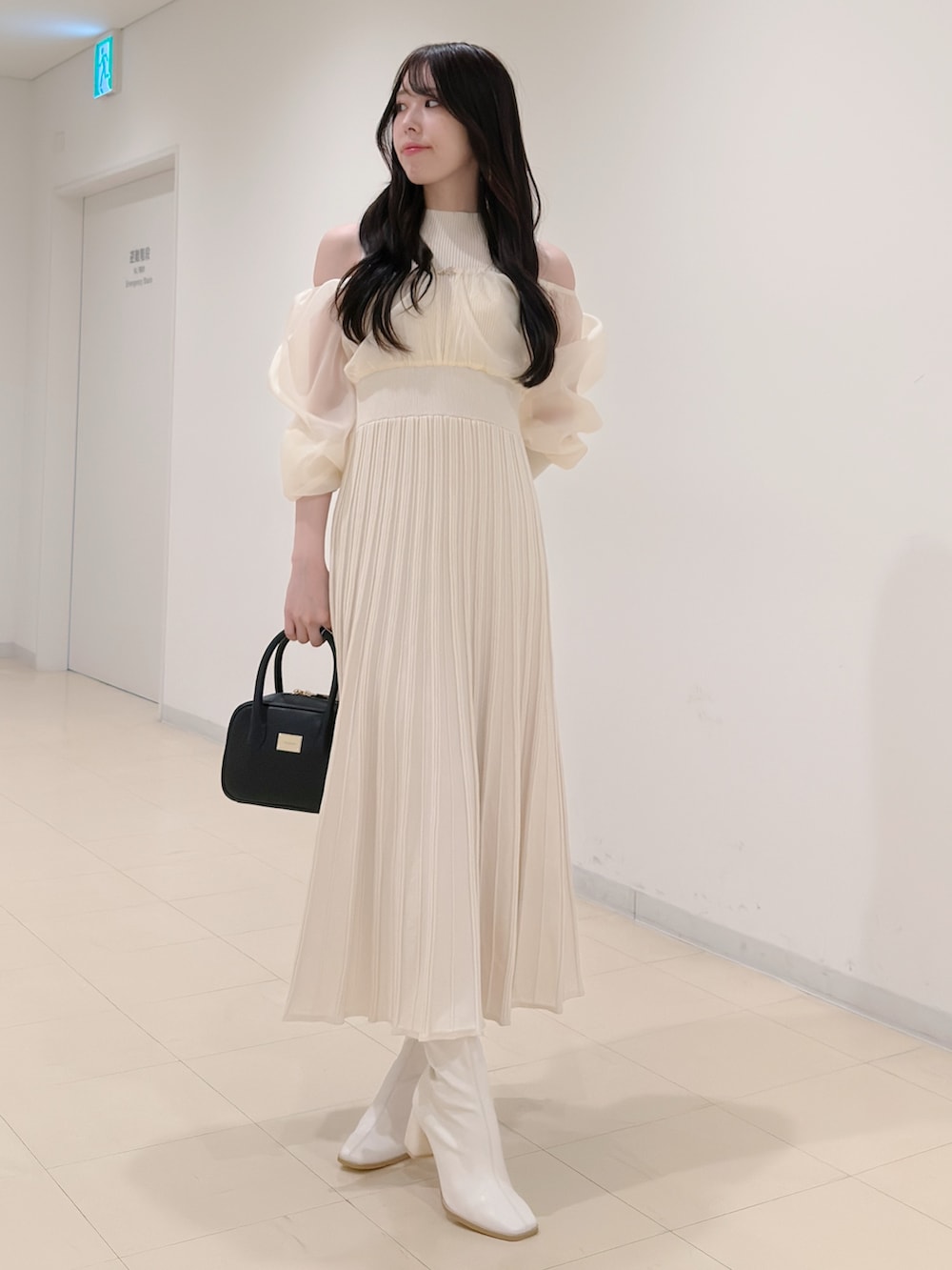 ホワイト系のワンピース、ブラック系のハンドバッグ、ホワイト系のブーツを着用したレディースの冬コーディネートの2枚目の写真