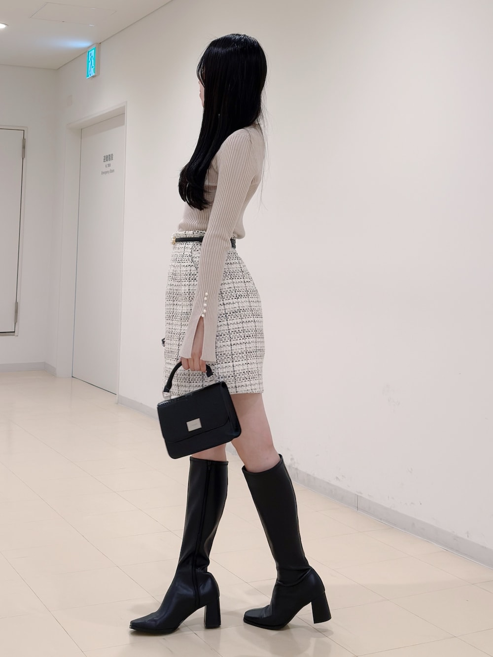 ベージュ系のニット/セーター、ホワイト系のスカート、ブラック系のハンドバッグを着用したレディースの秋コーディネートの4枚目の写真