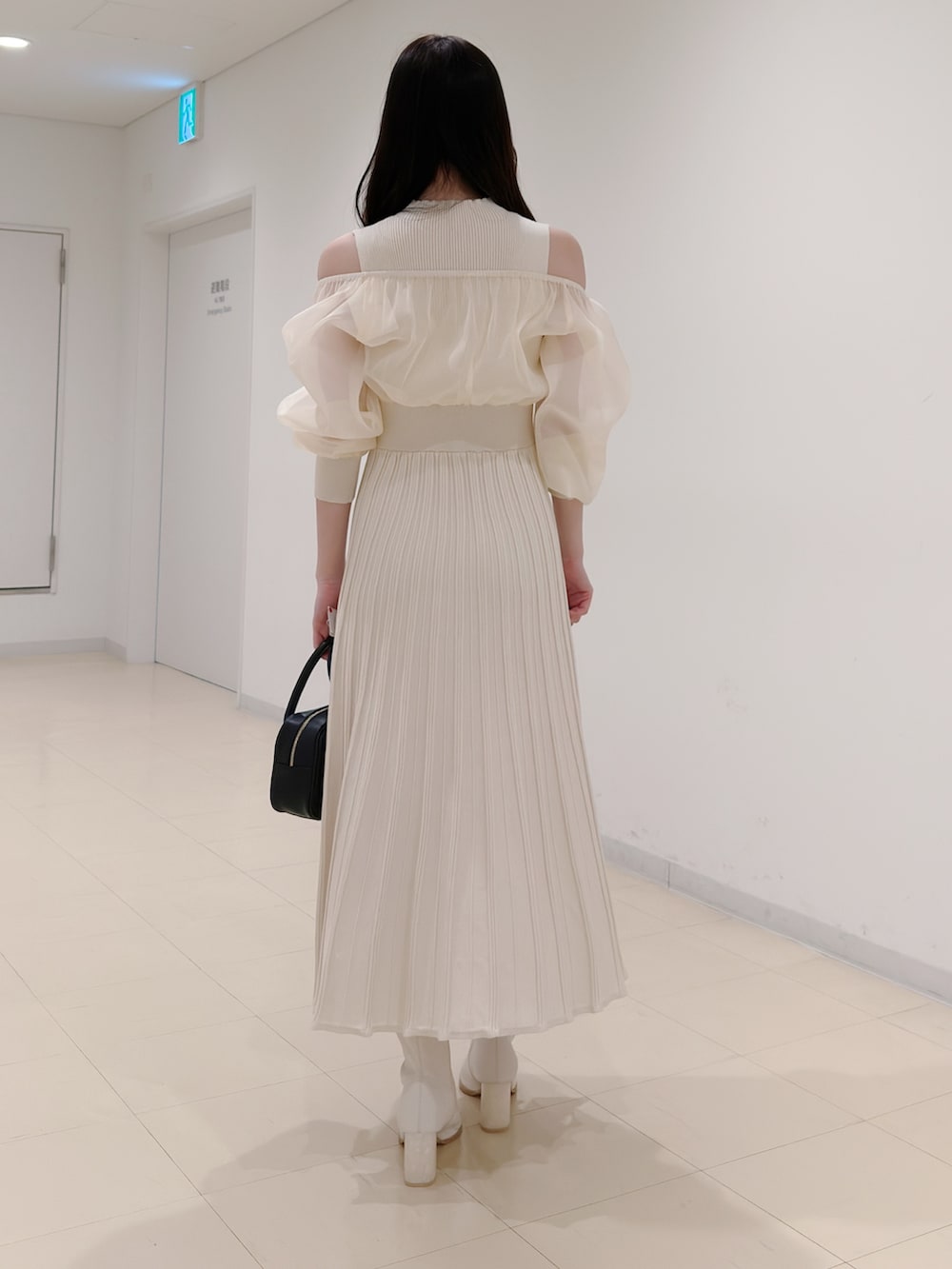 ホワイト系のワンピース、ブラック系のハンドバッグ、ホワイト系のブーツを着用したレディースの冬コーディネートの4枚目の写真