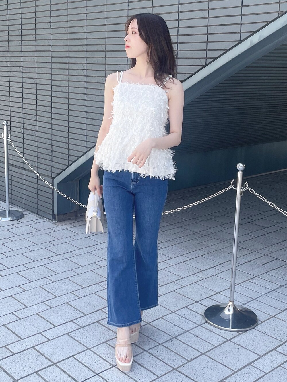 ホワイト系のキャミソール、ブルー系のデニムパンツ、その他のサンダルを着用したレディースの春コーディネートの4枚目の写真