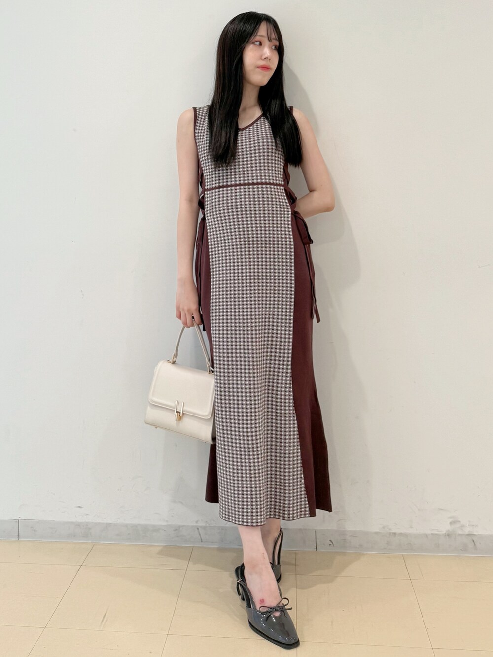 ブラウン系のワンピース、ホワイト系のハンドバッグ、グレー系のパンプスを着用したレディースの夏コーディネートの2枚目の写真