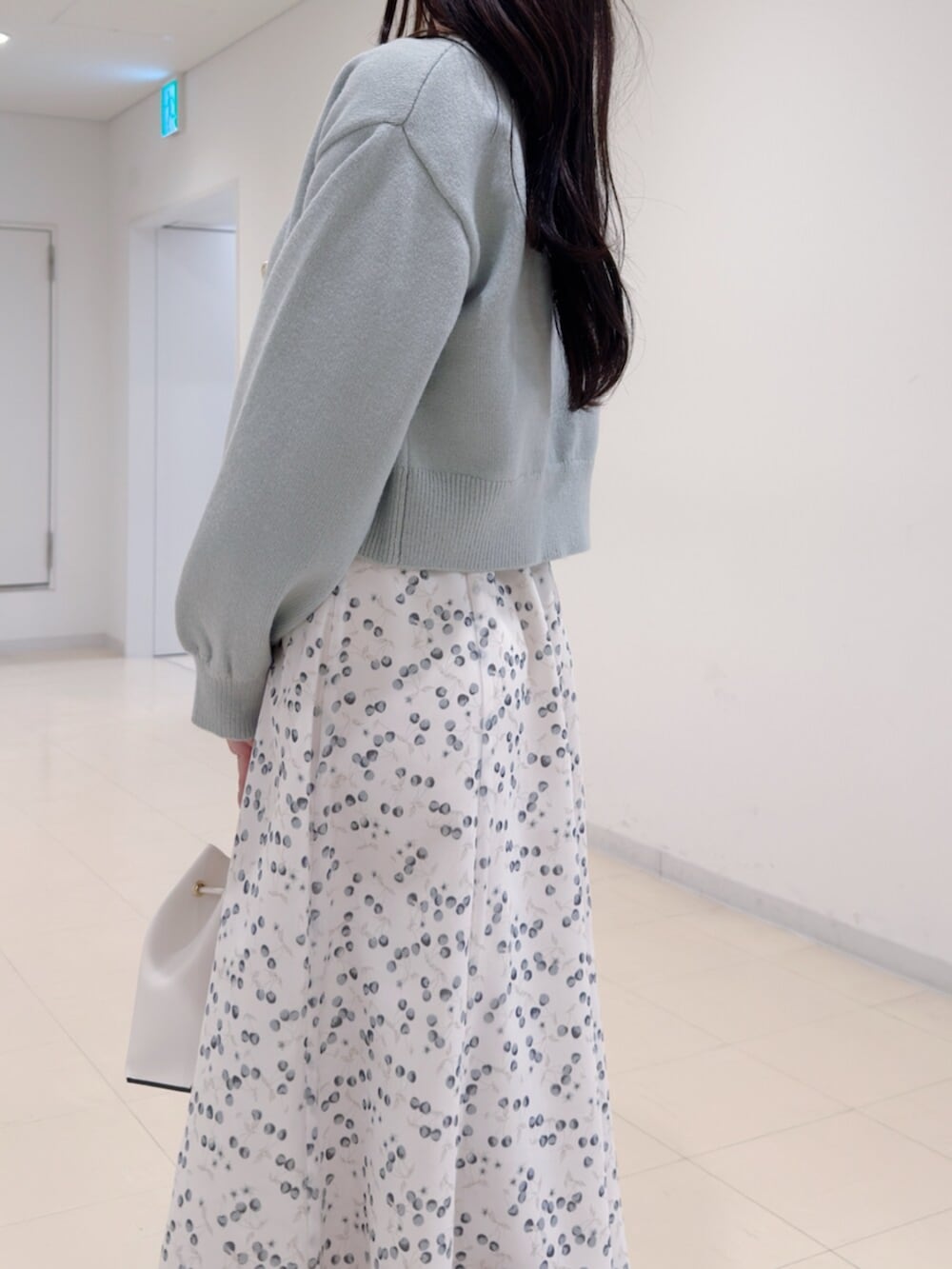 ホワイト系のショルダーバッグ、グリーン系のカーディガン/ボレロ、ホワイト系のワンピースを着用したレディースの冬コーディネートの6枚目の写真