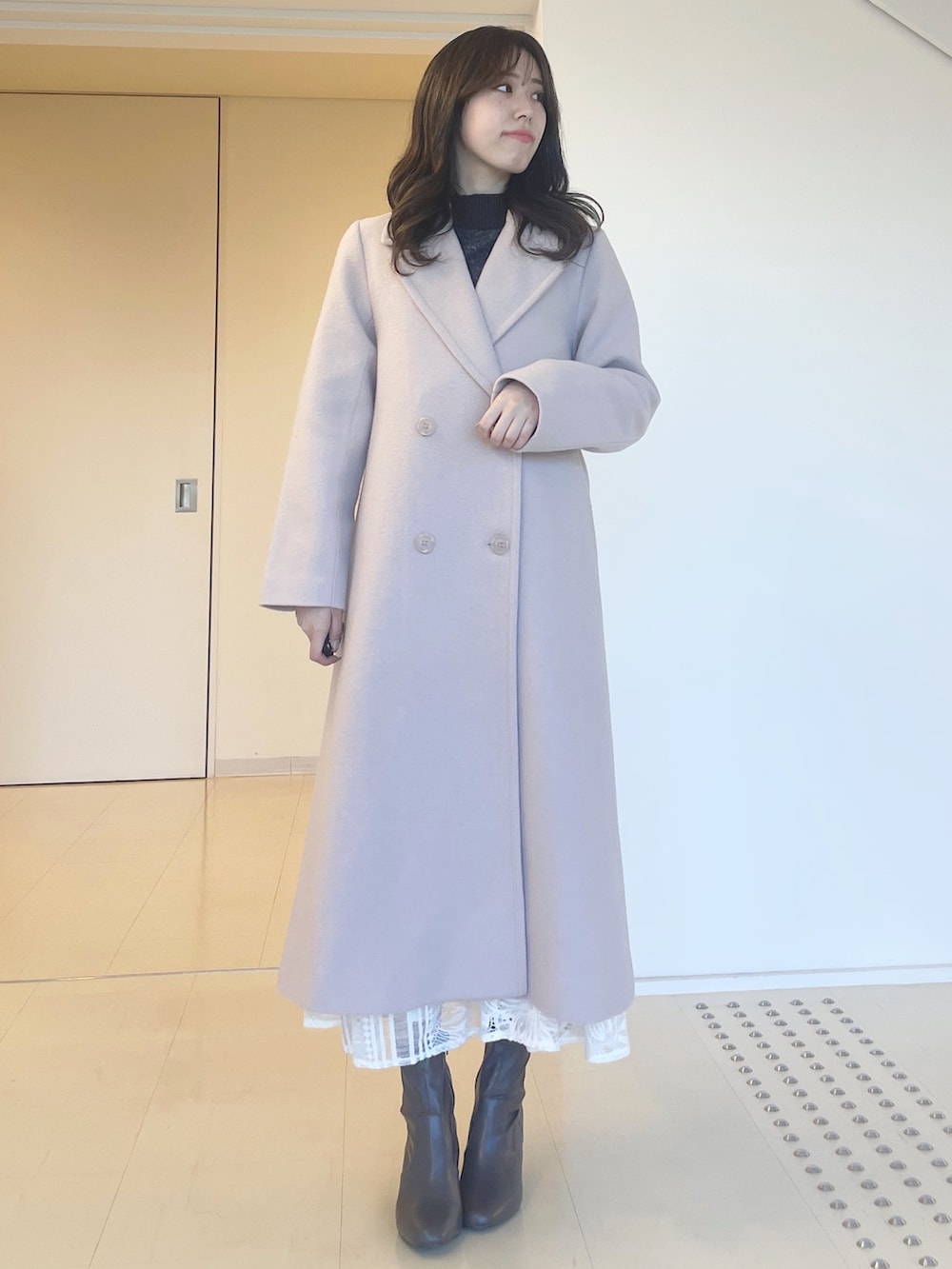 グレー系のニット/セーター、ホワイト系のスカート、ベージュ系のチェスターコートを着用したレディースの秋コーディネートの3枚目の写真
