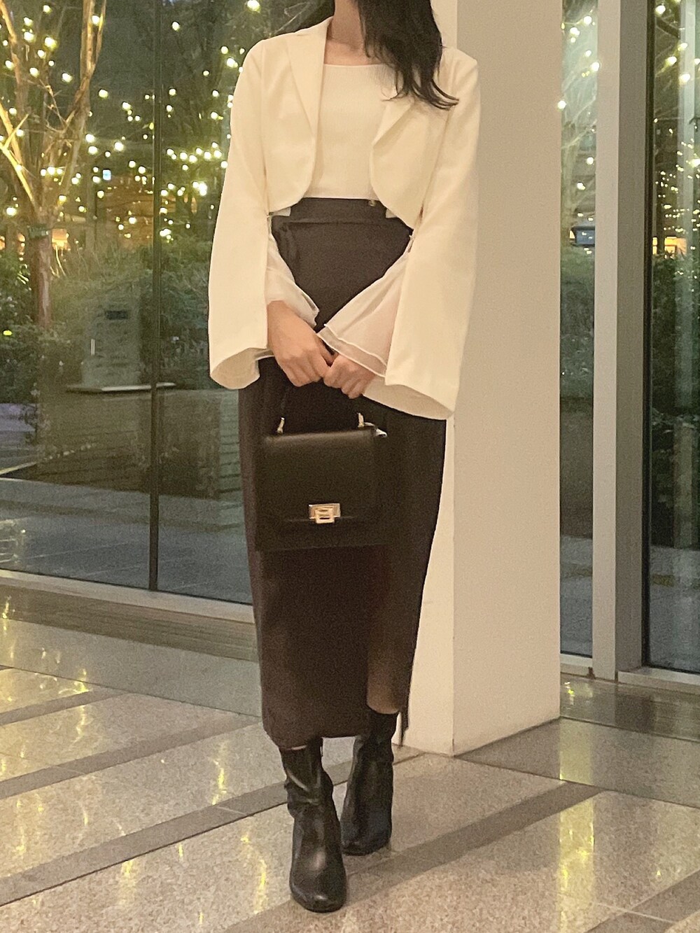 ホワイト系のテーラードジャケット、ホワイト系のニット/セーター、グレー系のスカートを着用したレディースの冬コーディネートの2枚目の写真