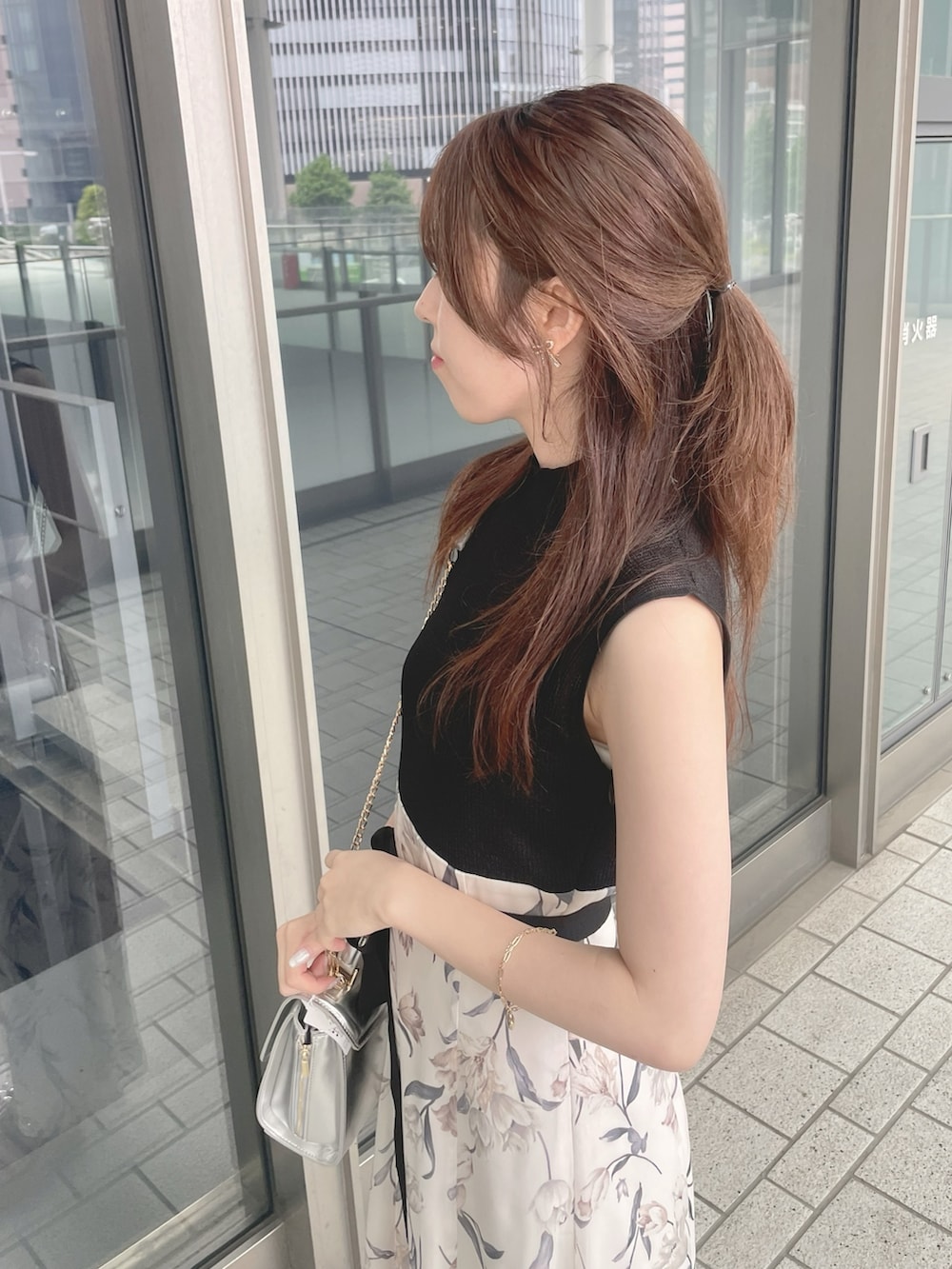 シルバー系のハンドバッグ、ブラック系のワンピース、ブラック系のサンダルを着用したレディースの春コーディネートの6枚目の写真