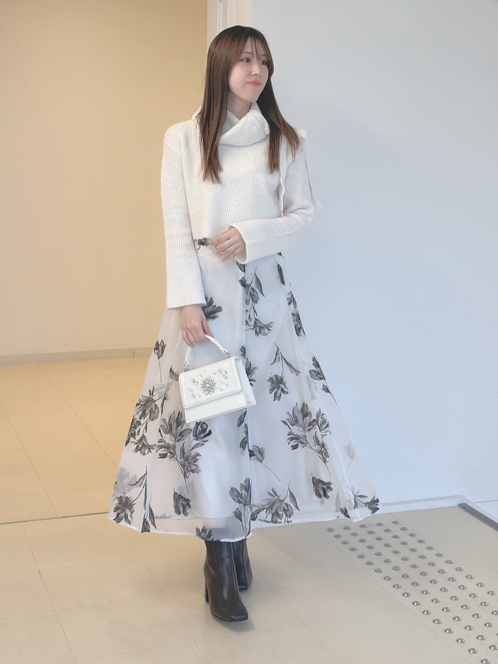 ホワイト系のニット/セーター、ホワイト系のスカート、ホワイト系のショルダーバッグを着用したレディースの秋コーディネートの2枚目の写真