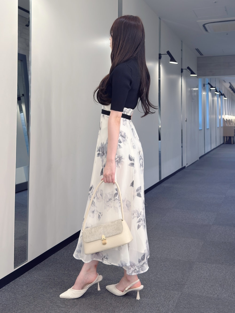 ブラック系のワンピース、ホワイト系のハンドバッグ、ホワイト系のパンプスを着用したレディースの春コーディネートの2枚目の写真