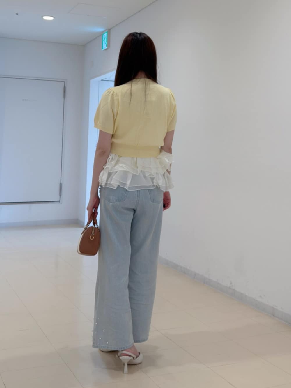 ブラウン系のハンドバッグ、ホワイト系のパンプス、ブルー系のデニムパンツを着用したレディースの夏コーディネートの4枚目の写真