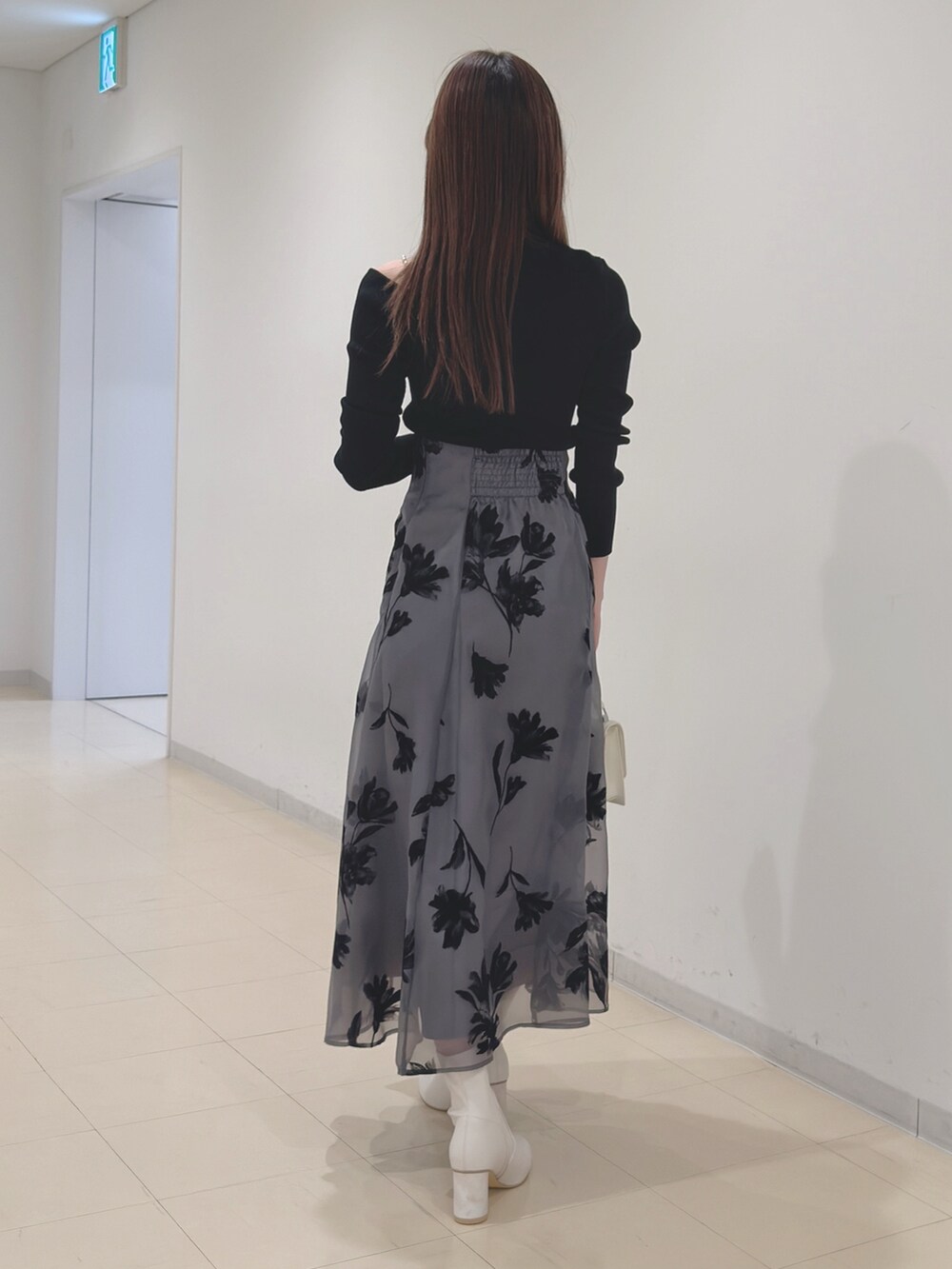 ブラック系のニット/セーター、グレー系のスカート、ホワイト系のショルダーバッグを着用したレディースの冬コーディネートの5枚目の写真