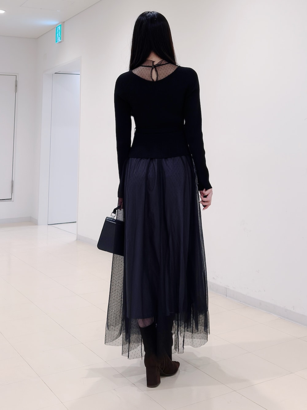 ブラック系のワンピース、ブラック系のハンドバッグ、ブラウン系のブーツを着用したレディースの秋コーディネートの5枚目の写真