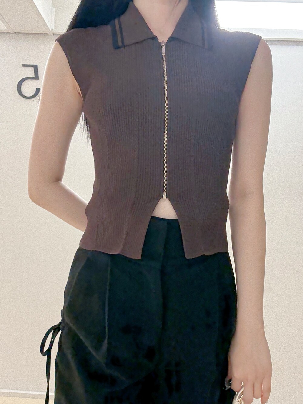 ブラウン系のニット/セーター、ブラック系のその他パンツ、ホワイト系のハンドバッグを着用したレディースの夏コーディネートの6枚目の写真