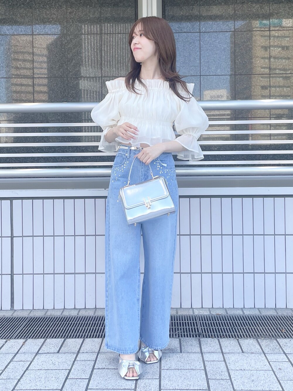 ブルー系のデニムパンツ、シルバー系のハンドバッグ、シルバー系のサンダルを着用したレディースの春コーディネートの3枚目の写真