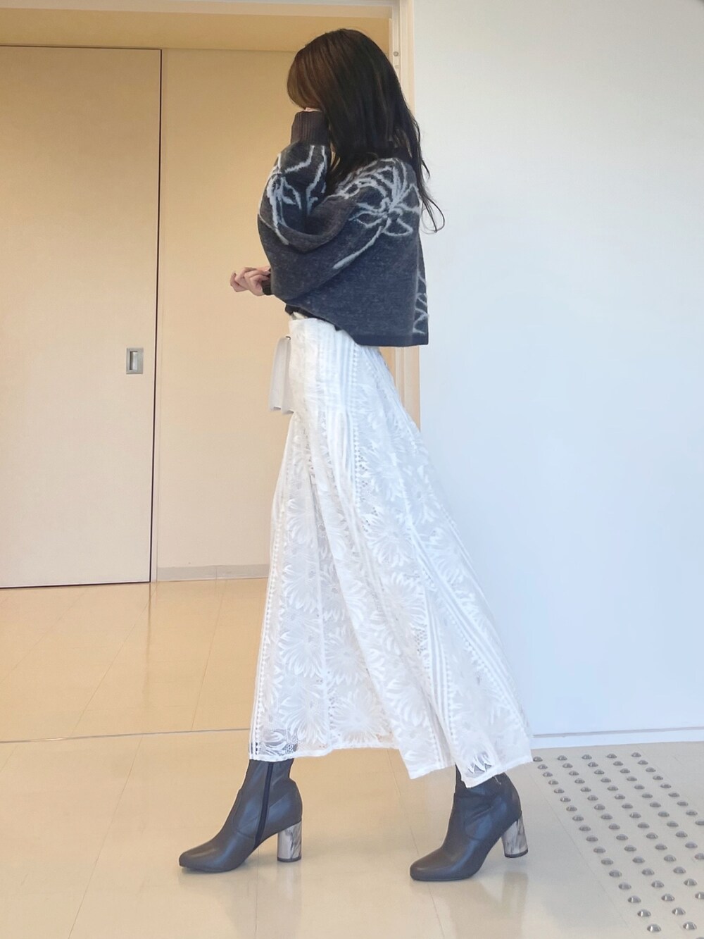 グレー系のニット/セーター、ホワイト系のスカート、ホワイト系のショルダーバッグを着用したレディースの秋コーディネートの4枚目の写真