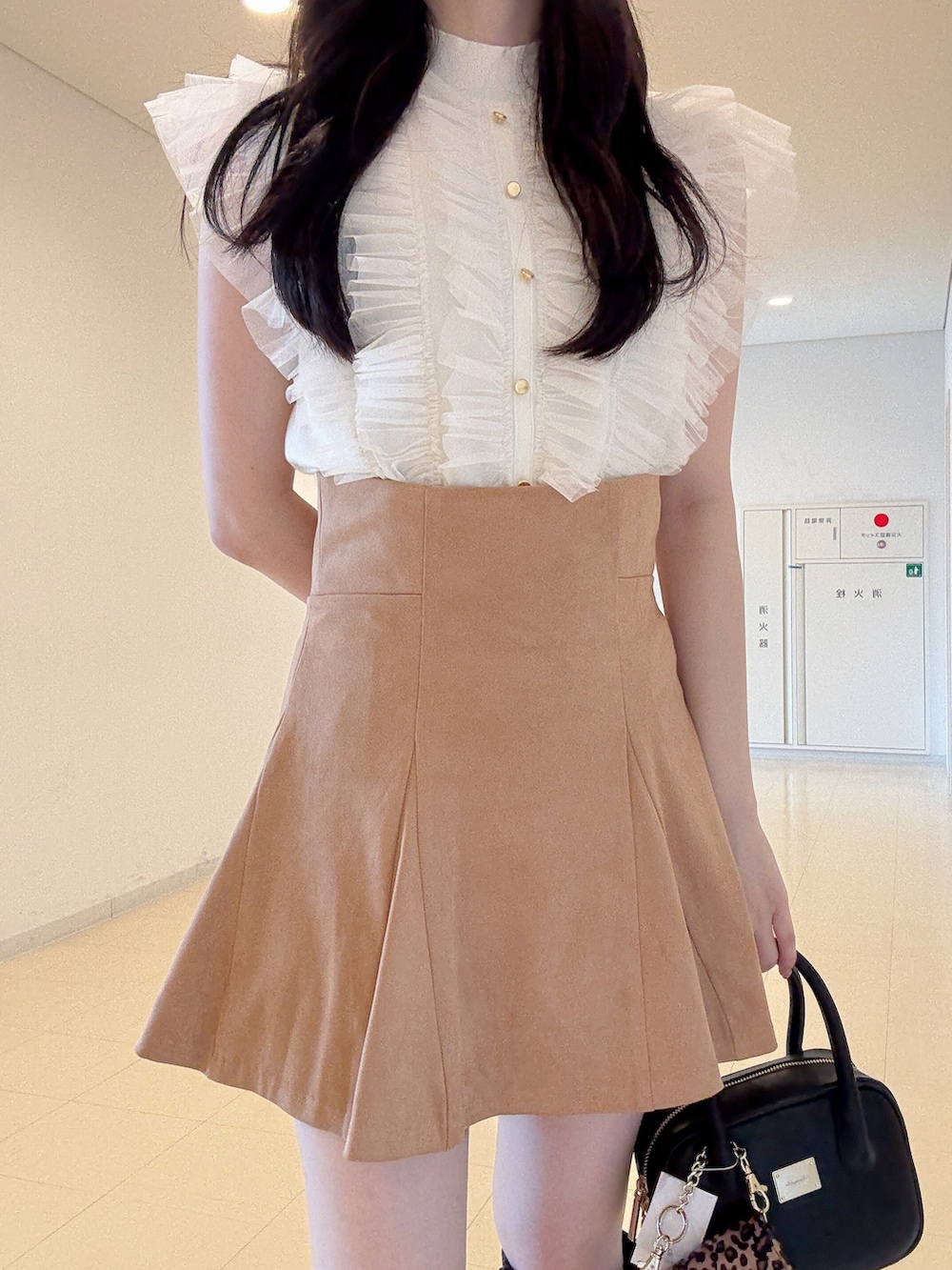 ホワイト系のニット/セーター、ブラック系のハンドバッグ、イエロー系のスカートを着用したレディースの夏コーディネートの6枚目の写真