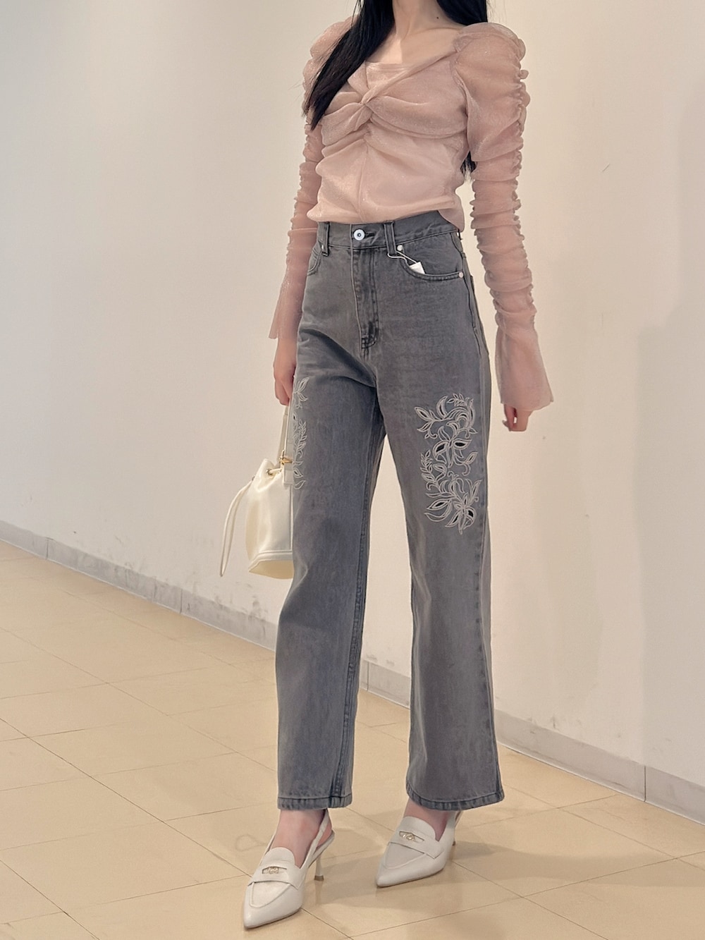 グレー系のデニムパンツ、ホワイト系のハンドバッグ、ピンク系のTシャツ/カットソーを着用したレディースの夏コーディネートの3枚目の写真