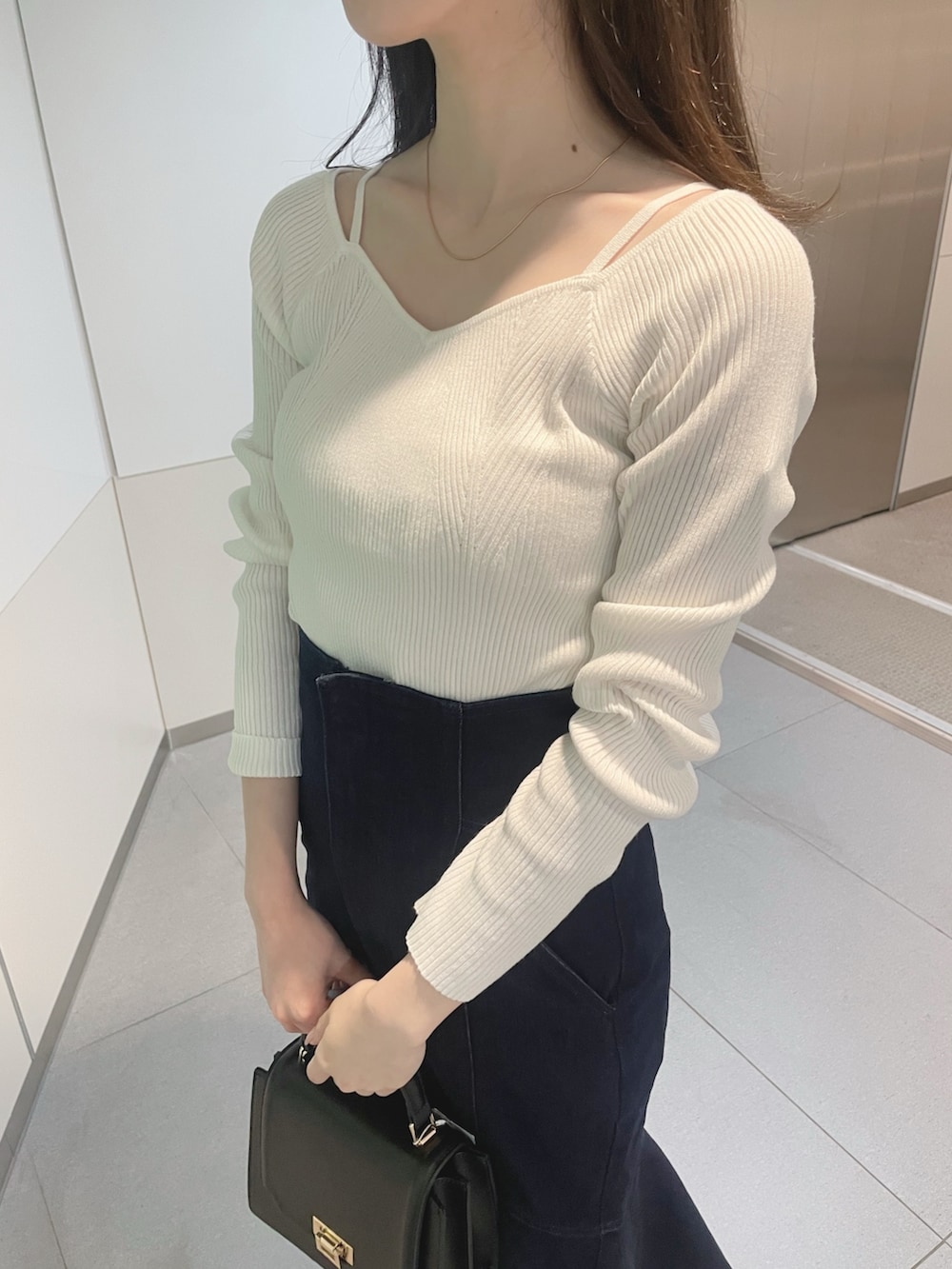 ブラック系のハンドバッグ、ホワイト系のニット/セーター、ブルー系のデニムスカートを着用したレディースの冬コーディネートの6枚目の写真