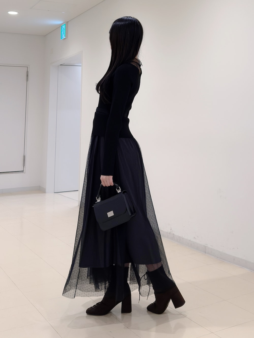 ブラック系のワンピース、ブラック系のハンドバッグ、ブラウン系のブーツを着用したレディースの秋コーディネートの4枚目の写真