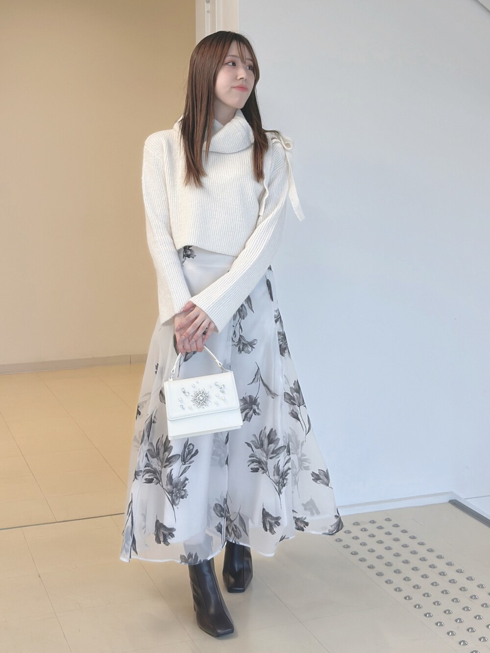 ホワイト系のニット/セーター、ホワイト系のスカート、ホワイト系のショルダーバッグを着用したレディースの秋コーディネートの3枚目の写真