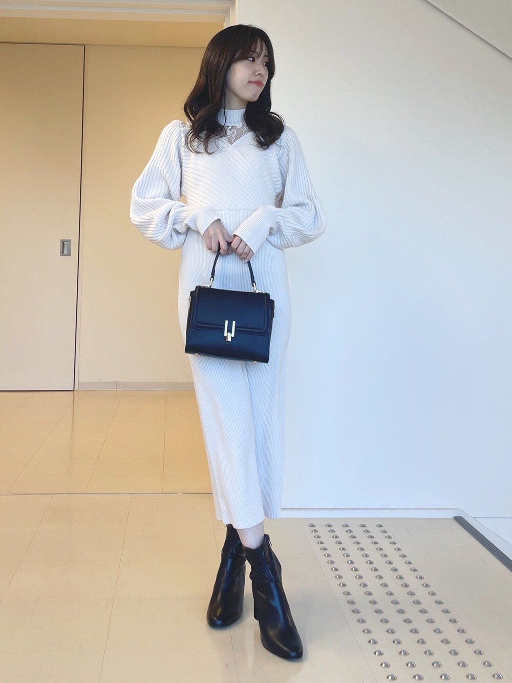 ホワイト系のワンピース、ブラック系のブーツ、ブラック系のショルダーバッグを着用したレディースの秋コーディネートの2枚目の写真