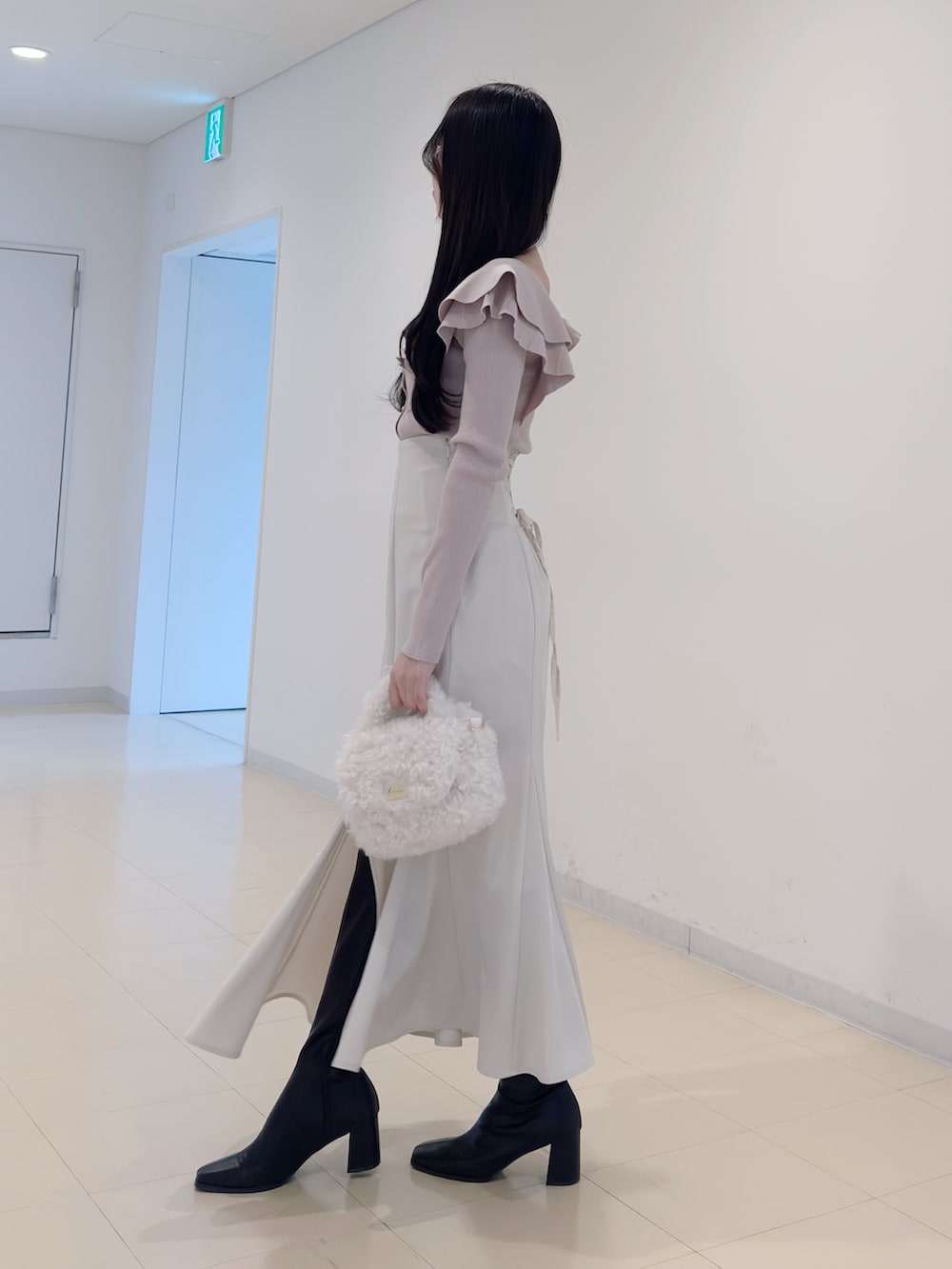 ベージュ系のニット/セーター、ホワイト系のスカート、ホワイト系のハンドバッグを着用したレディースの冬コーディネートの3枚目の写真