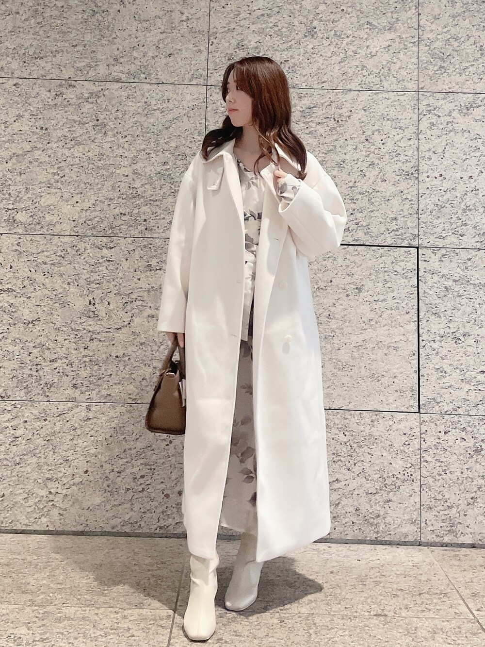 ホワイト系のステンカラーコート、ホワイト系のワンピースを着用したレディースの冬コーディネートの2枚目の写真